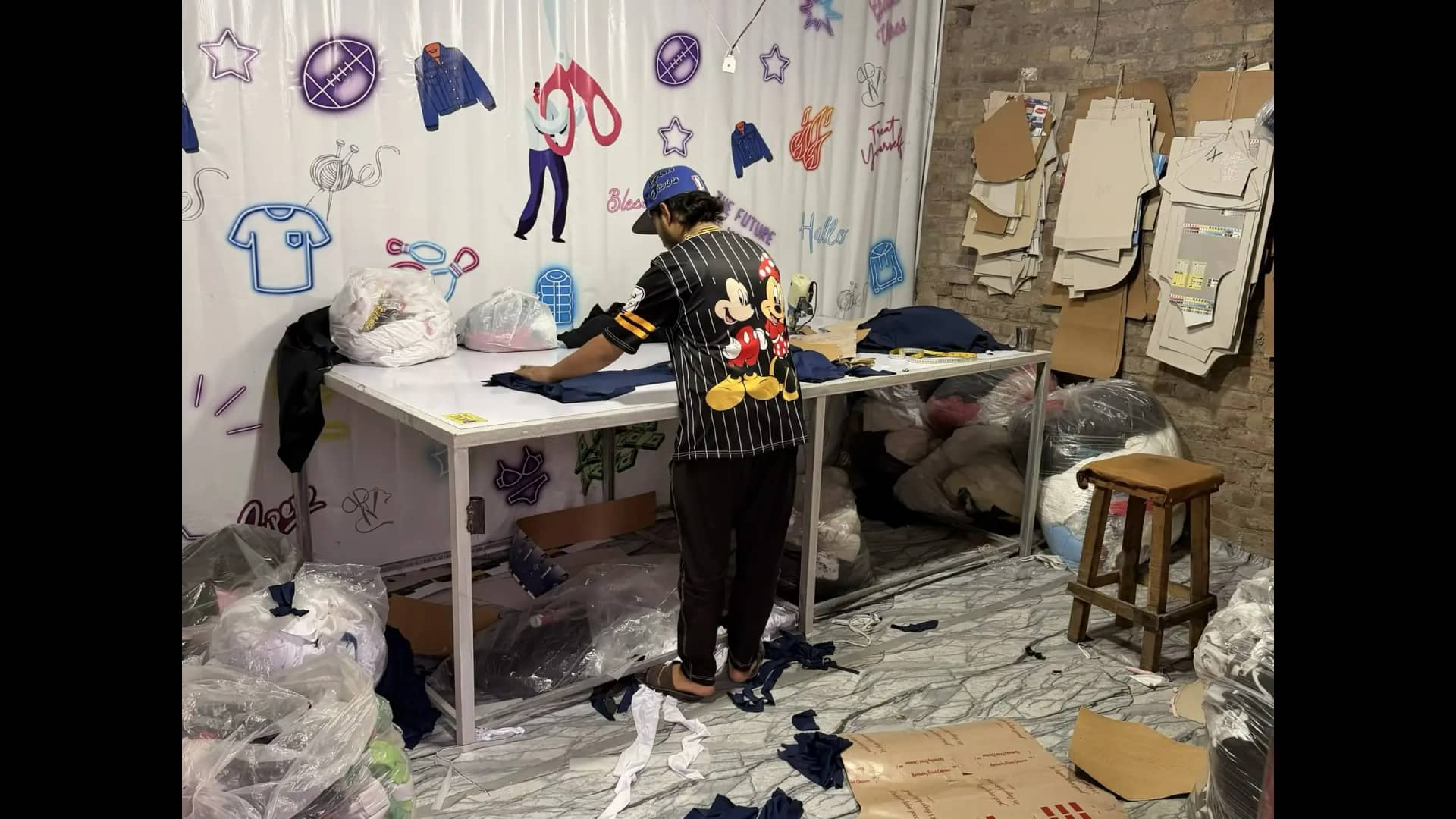 Worker preparing custom hoodie at cut-and-sew design table — Mughal Apparel Sialkot