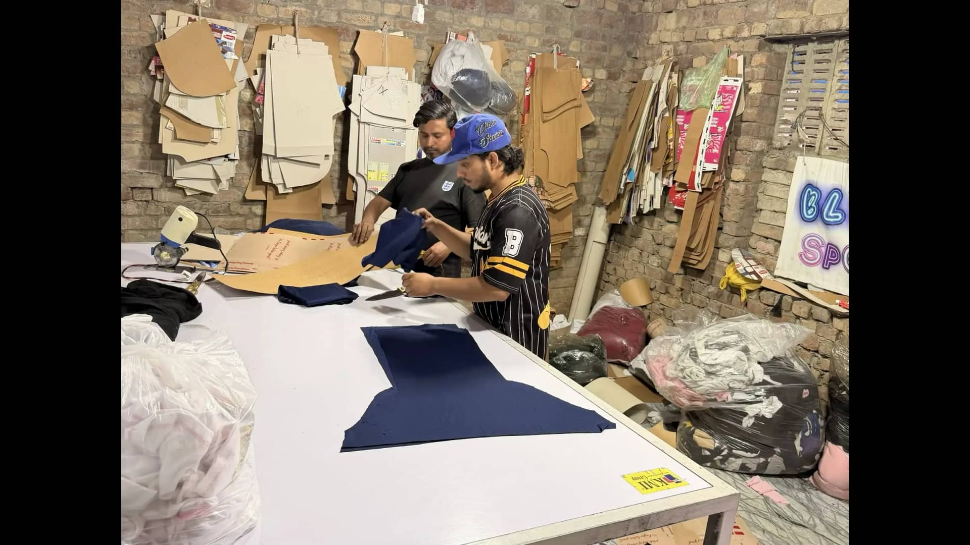 Quality inspection of cut fabric pieces inside Mughal Apparel pattern room — Sialkot Pakistan