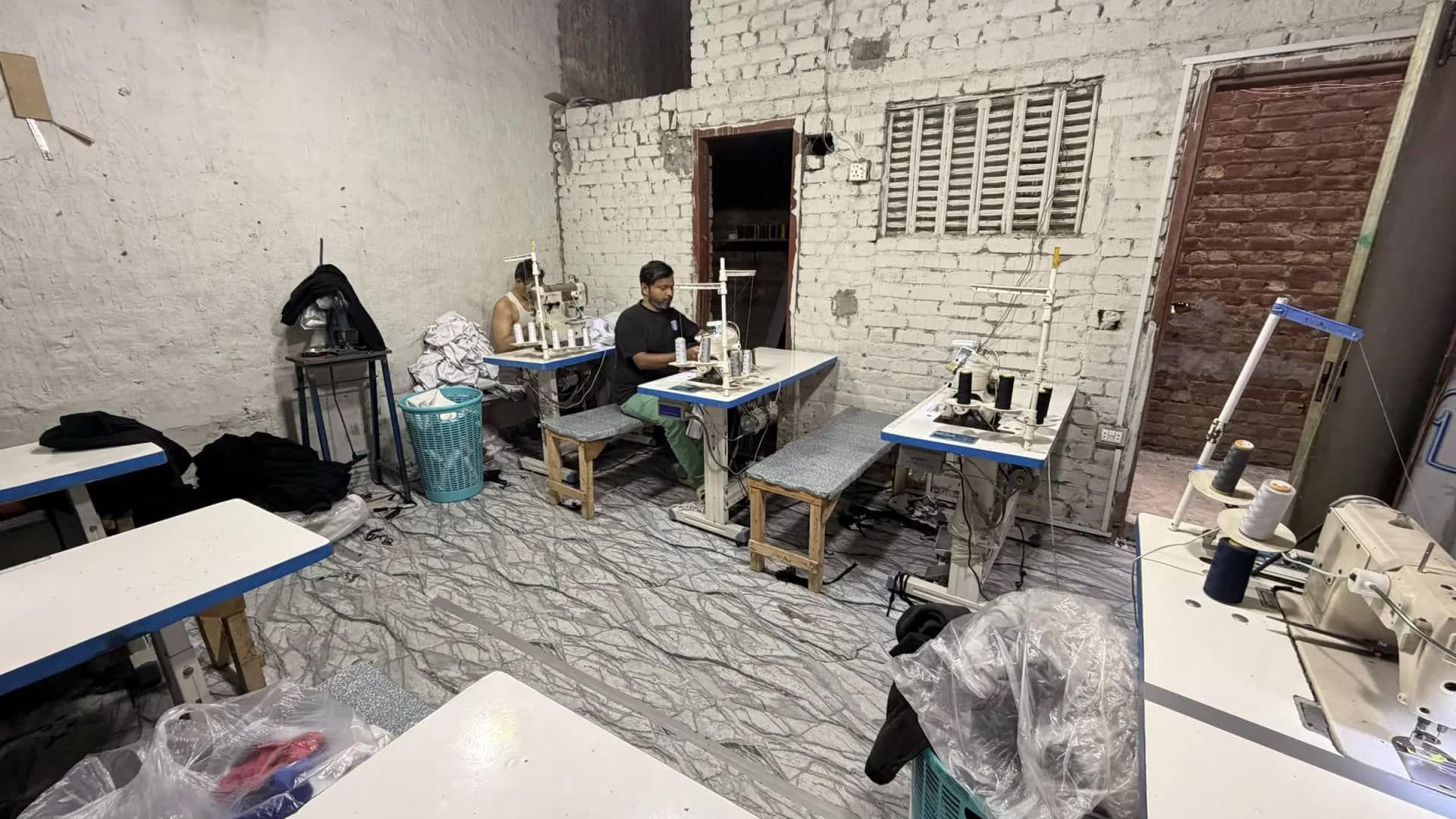 Industrial sewing machines and operator on production floor — Mughal Apparel manufacturing